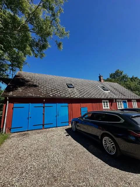 Rött uthus med blå portar och pannor på taket