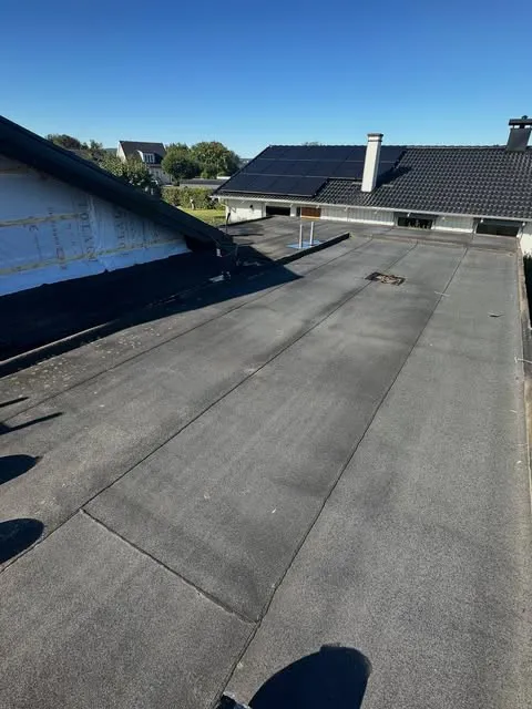 Platt papptak med en villa med solpaneler i bakgrunden